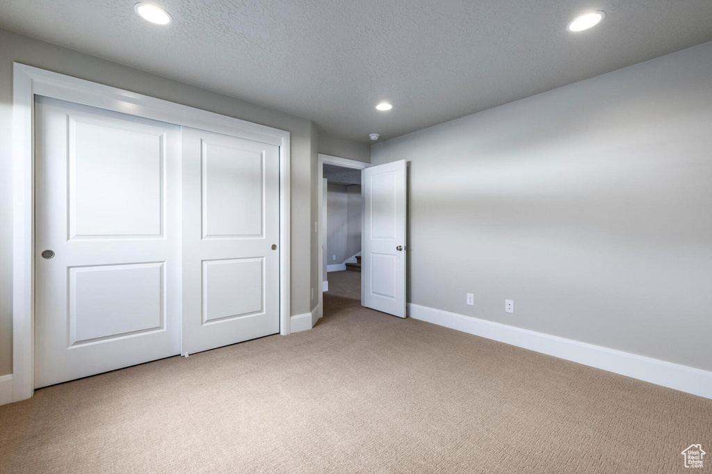 Unfurnished bedroom with light carpet, baseboards, recessed lighting, and a closet