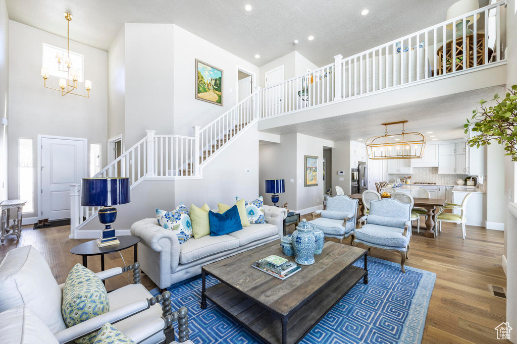 Living room with a chandelier, a high ceiling, stairway, baseboards, and recessed lighting