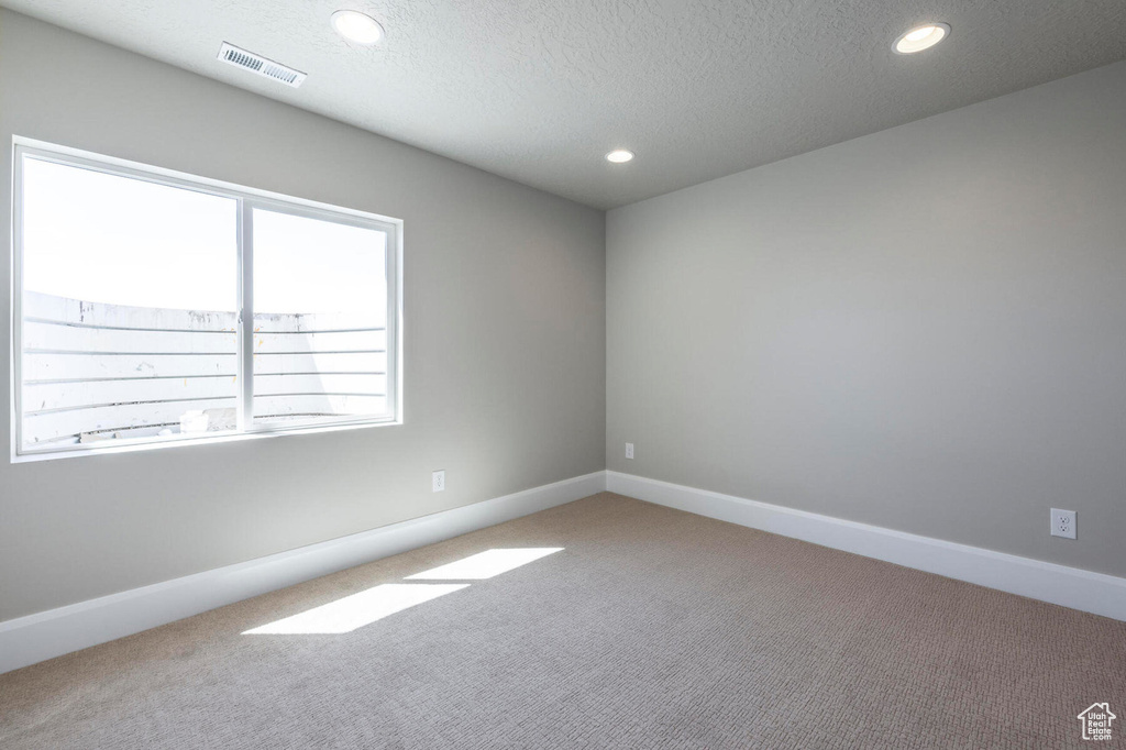 Carpeted spare room featuring a textured ceiling, recessed lighting, and baseboards