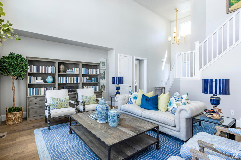 Living room featuring a high ceiling, stairway, wood finished floors, and a chandelier