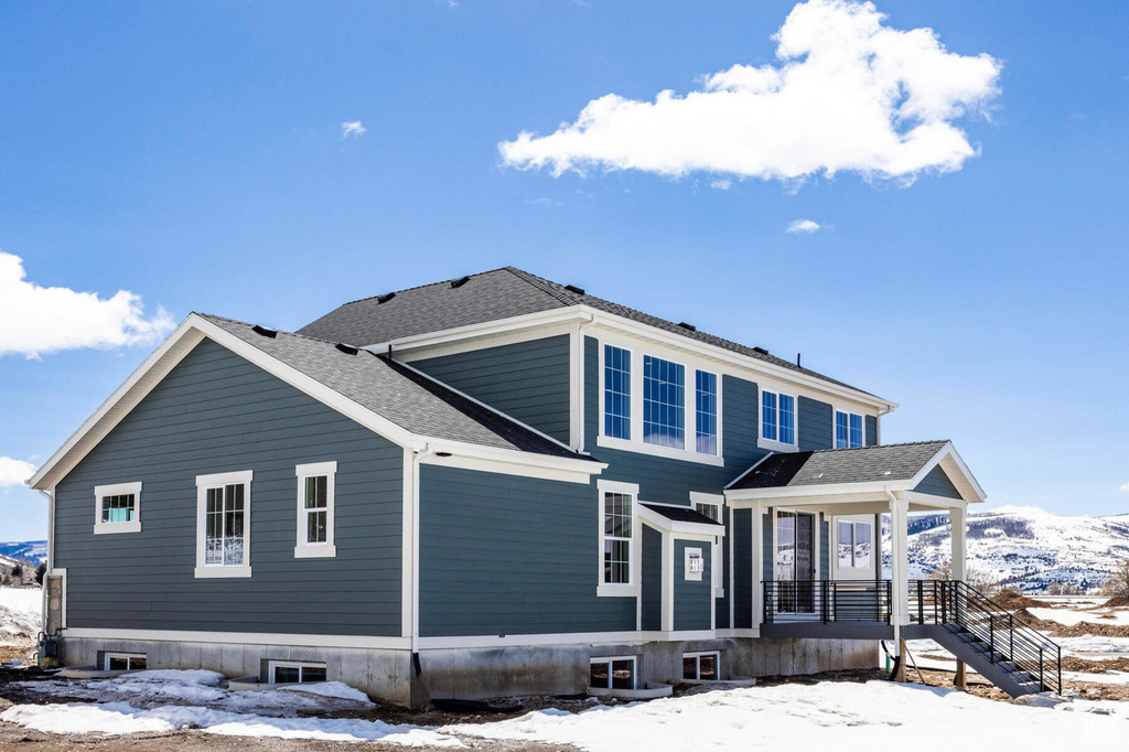 Snow covered property featuring a shingled roof