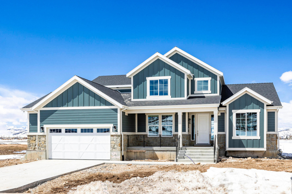 Craftsman-style house with board and batten siding, stone siding, covered porch, and a garage