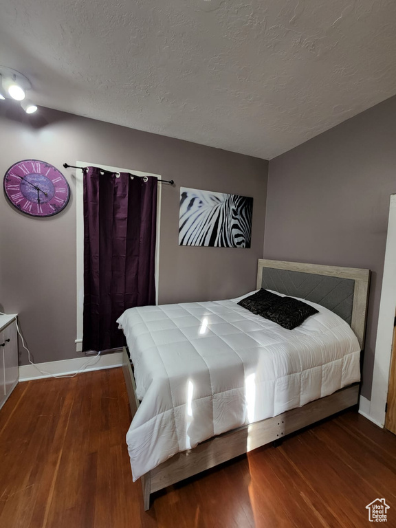 Bedroom with wood finished floors, a textured ceiling, and baseboards