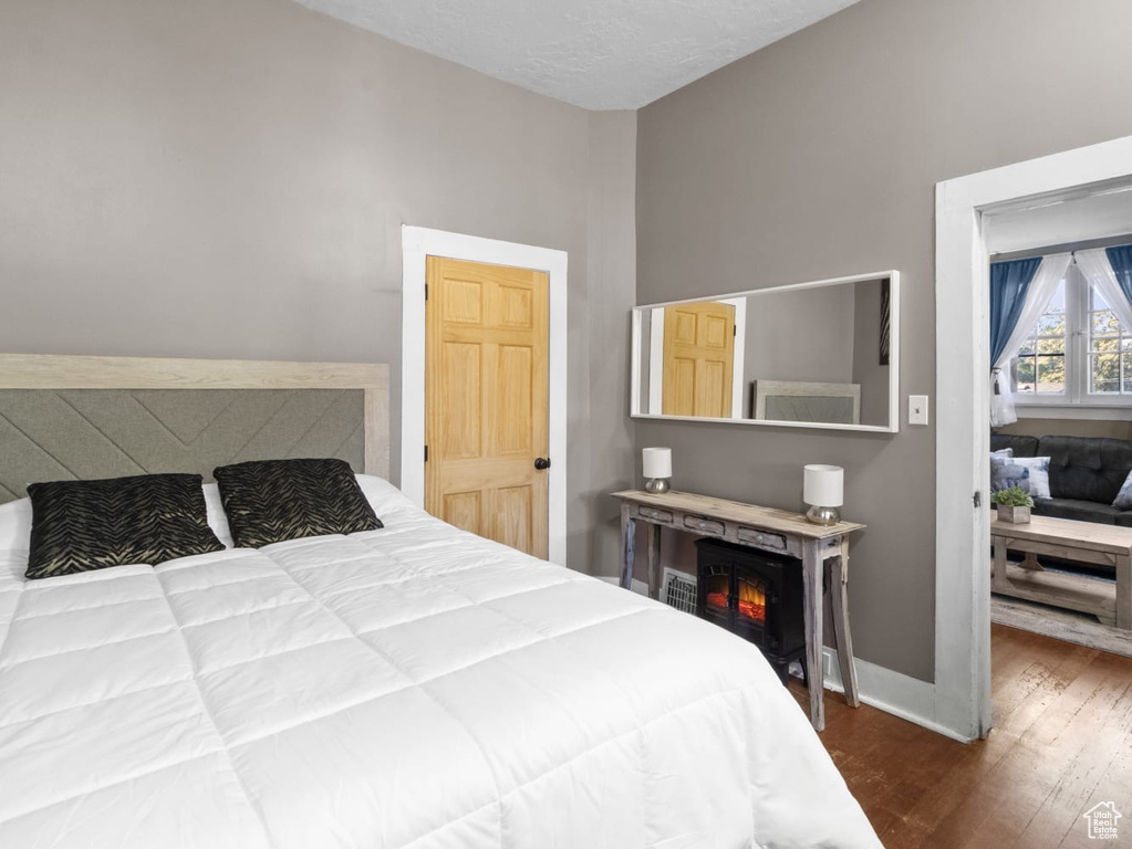 Bedroom featuring wood finished floors, baseboards, and a lit fireplace