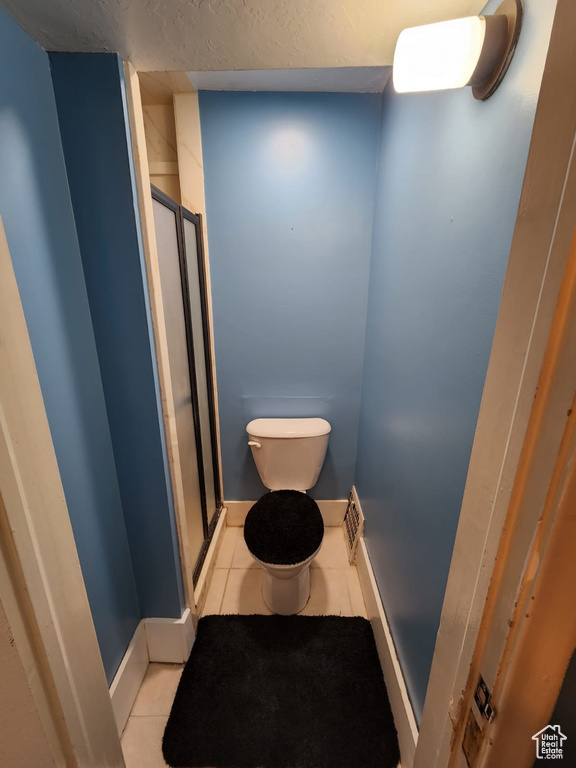 Full bath with toilet, tile patterned floors, a stall shower, and baseboards