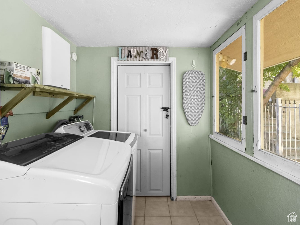 Laundry room featuring independent washer and dryer, light tile patterned floors, and baseboards