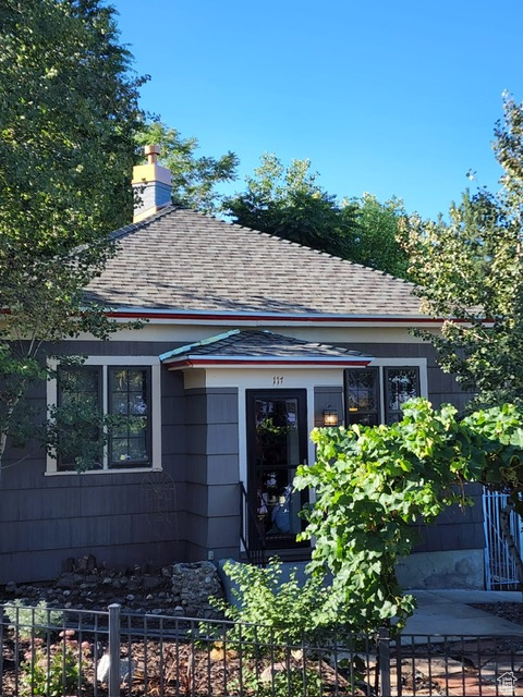View of front of property featuring a shingled roof and a chimney