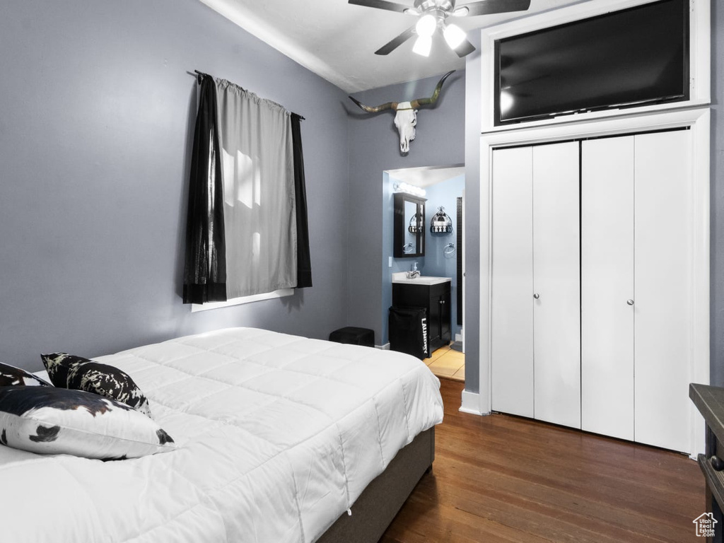 Bedroom featuring wood finished floors, ensuite bath, a closet, and a ceiling fan
