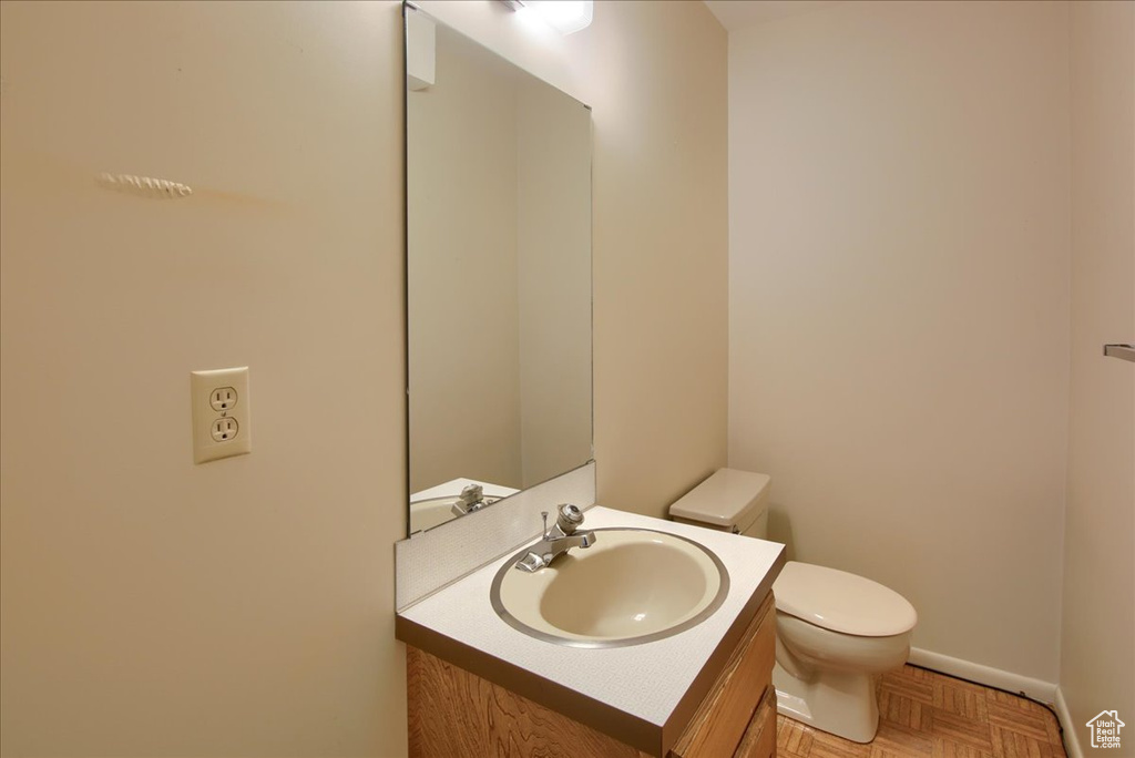 Bathroom featuring toilet, vanity, and baseboards