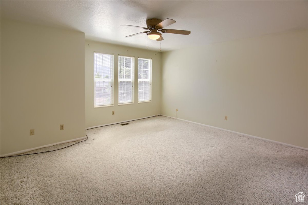Unfurnished room with a ceiling fan, light carpet, and baseboards