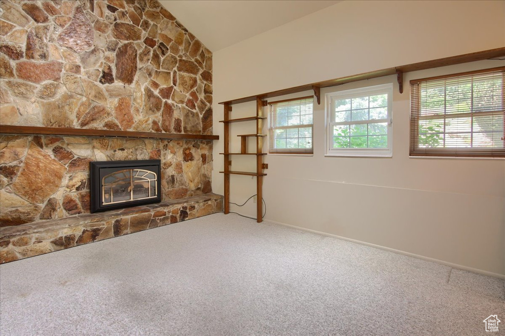 Unfurnished living room with carpet flooring, vaulted ceiling, a fireplace, and baseboards