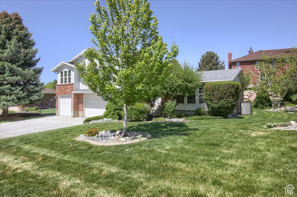 Obstructed view of property with concrete driveway, a garage, a front yard, and brick siding