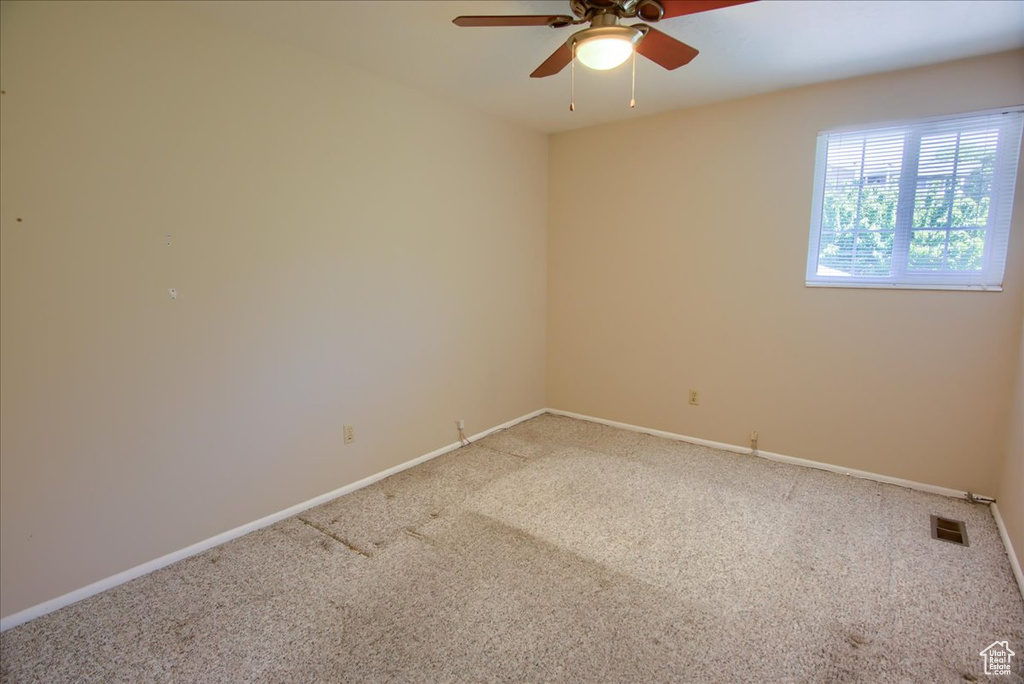 Carpeted spare room with ceiling fan and baseboards