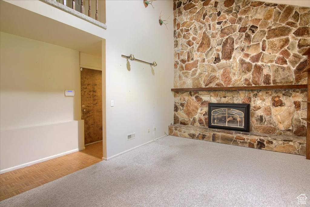 Unfurnished living room with a stone fireplace, carpet floors, and baseboards