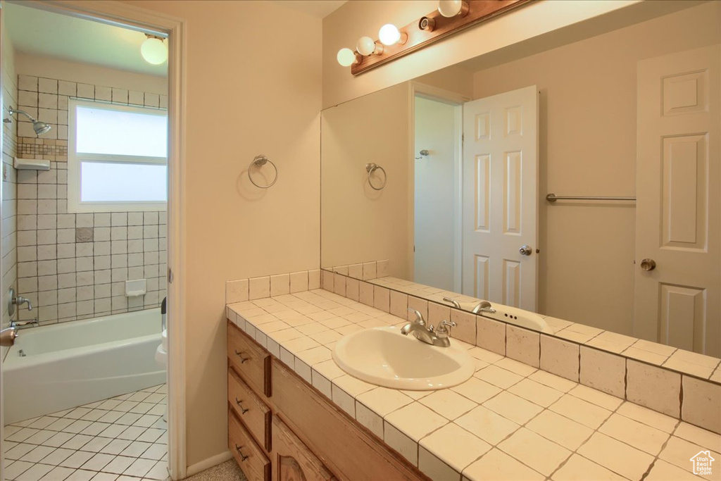 Bathroom featuring vanity, tile patterned flooring, and shower / washtub combination