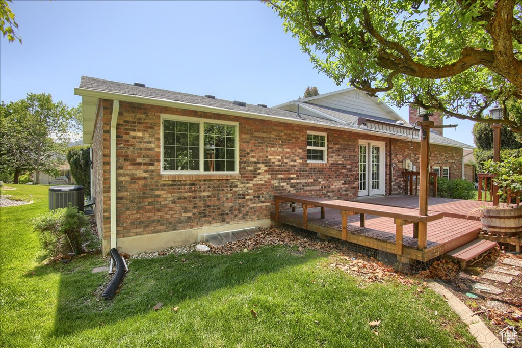 Rear view of house with french doors, brick siding, a lawn, and a wooden deck