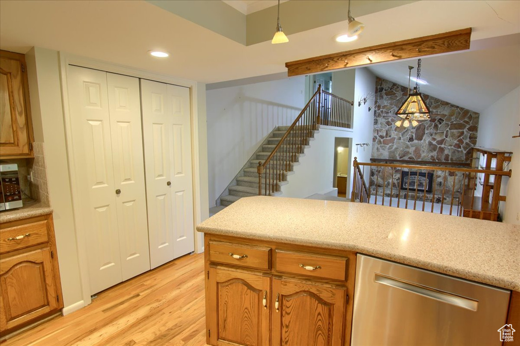 Kitchen with stainless steel appliances, light wood-type flooring, vaulted ceiling, pendant lighting, and brown cabinetry