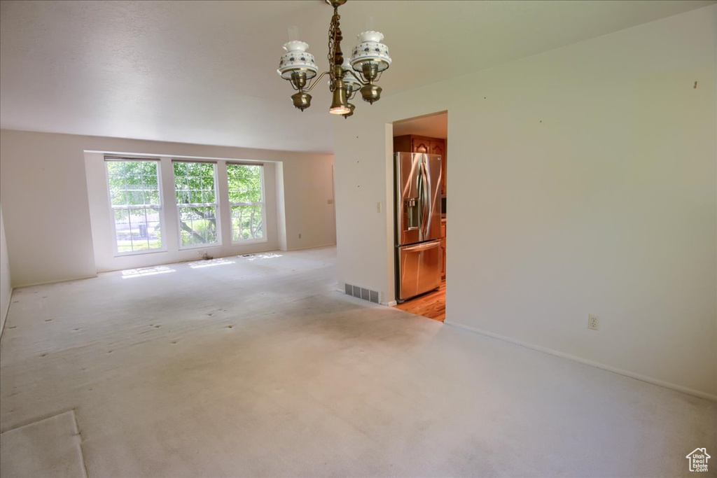 Unfurnished room featuring a chandelier and light colored carpet