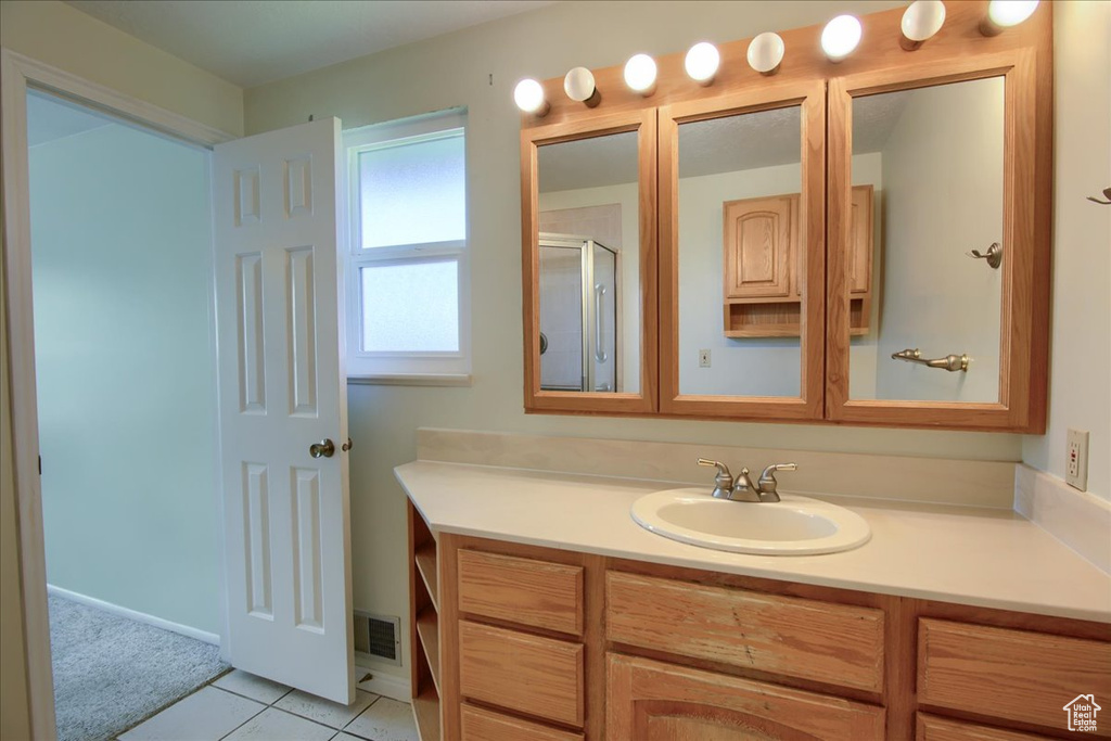 Bathroom featuring vanity, a shower with door, and tile patterned floors
