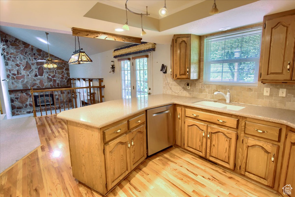 Kitchen with stainless steel dishwasher, a sink, light wood-style flooring, a peninsula, and vaulted ceiling