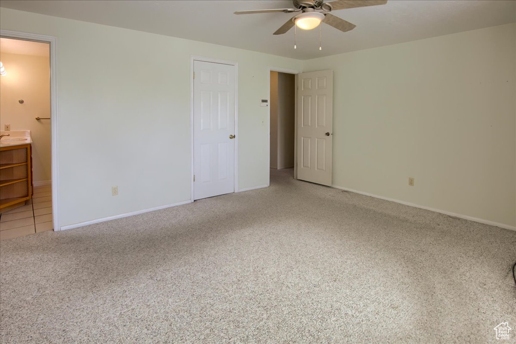 Unfurnished bedroom with light carpet, ensuite bath, baseboards, and a ceiling fan