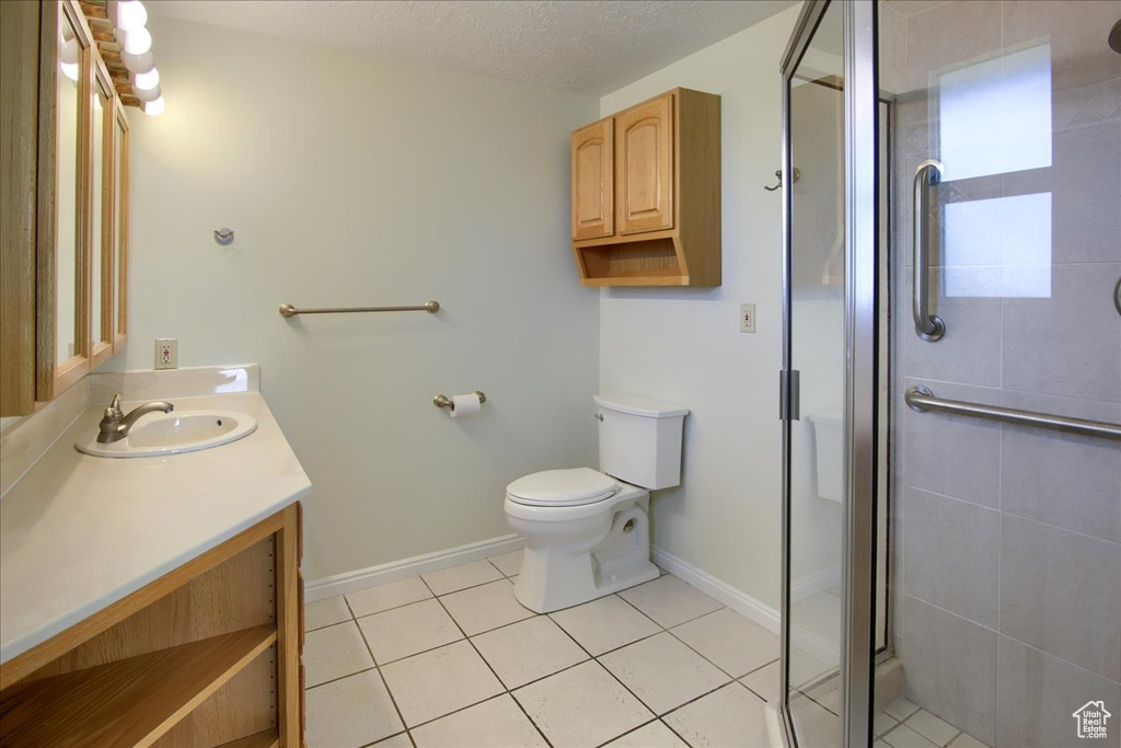 Bathroom with vanity, a shower stall, toilet, tile patterned flooring, and baseboards