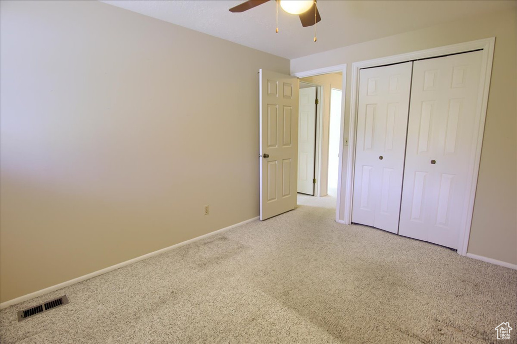 Unfurnished bedroom featuring light carpet, baseboards, a closet, and ceiling fan