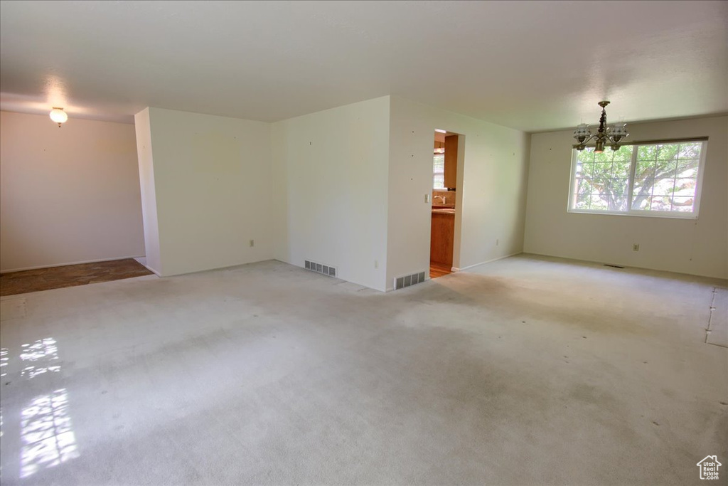 Spare room featuring a chandelier and light colored carpet