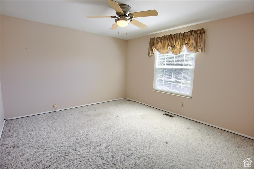 Empty room with carpet, a ceiling fan, and baseboards