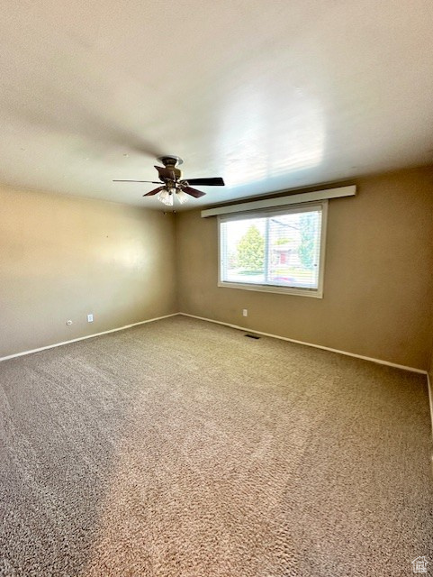 Carpeted spare room featuring baseboards and ceiling fan