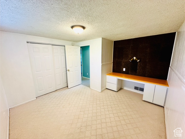 Unfurnished bedroom featuring a closet, baseboards, carpet floors, and a textured ceiling