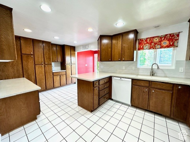Kitchen with white dishwasher, a sink, a peninsula, light countertops, and recessed lighting