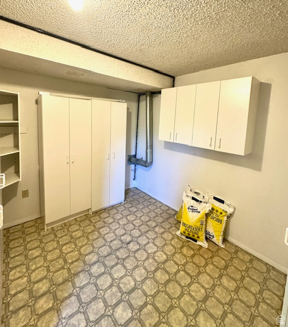 Finished below grade area with light flooring and a textured ceiling