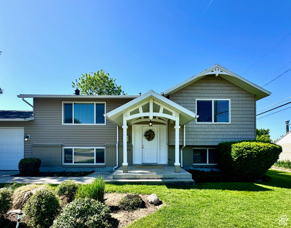Tri-level home featuring a front yard, brick siding, and an attached garage