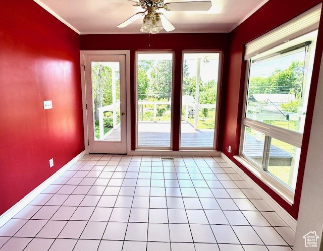 Doorway with a ceiling fan, plenty of natural light, baseboards, and ornamental molding