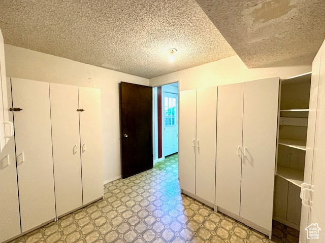 Unfurnished bedroom with light floors, a textured ceiling, and a closet