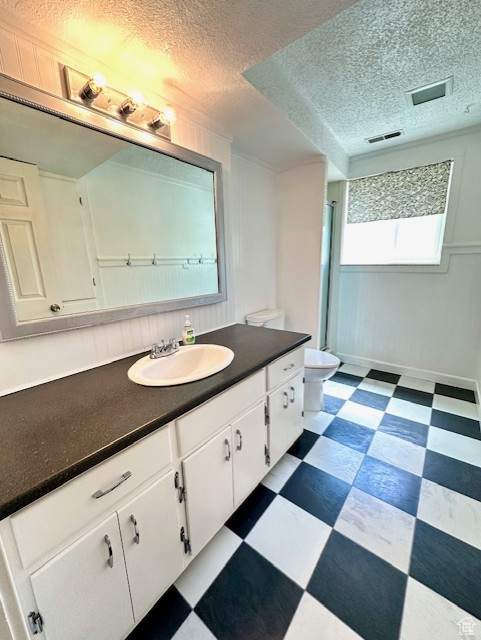 Full bathroom with tile patterned floors, vanity, toilet, a textured ceiling, and baseboards