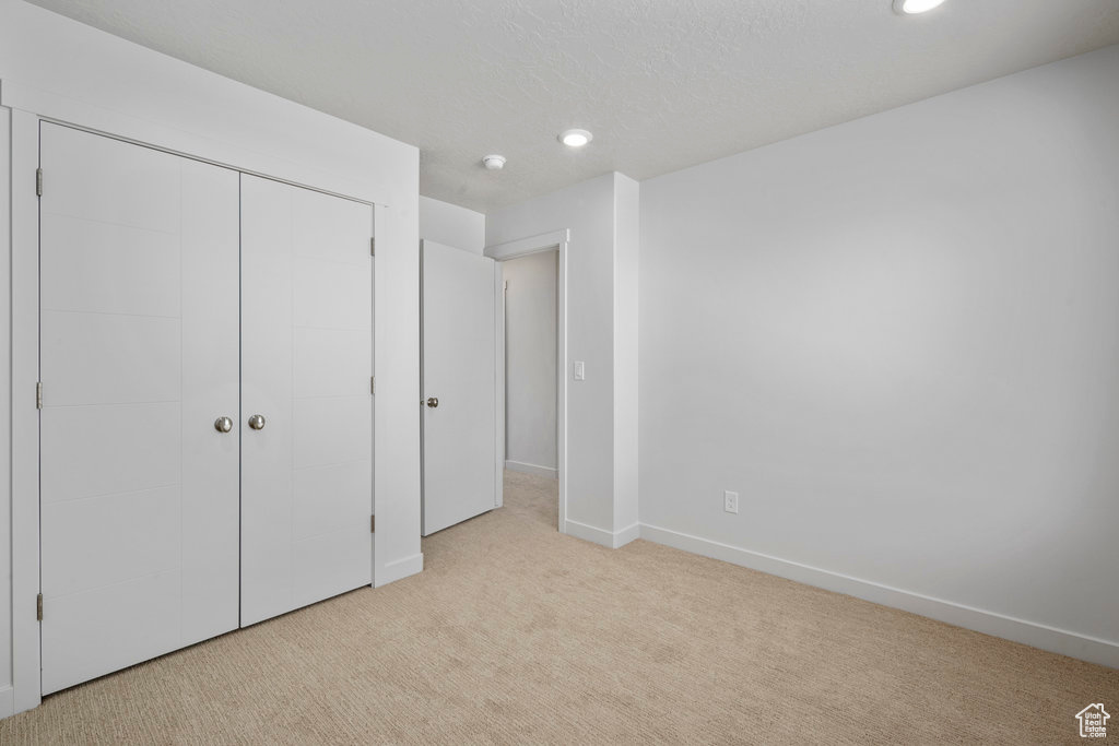 Unfurnished bedroom with carpet flooring, recessed lighting, baseboards, and a closet