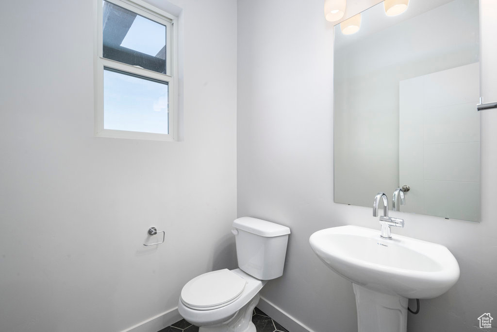 Bathroom with baseboards, toilet, and a sink