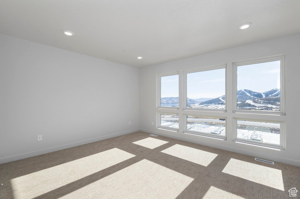 Empty room with a mountain view, carpet floors, plenty of natural light, recessed lighting, and baseboards