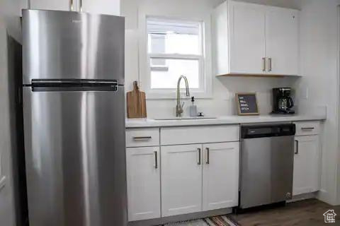 Kitchen featuring stainless steel appliances, a sink, and white cabinetry