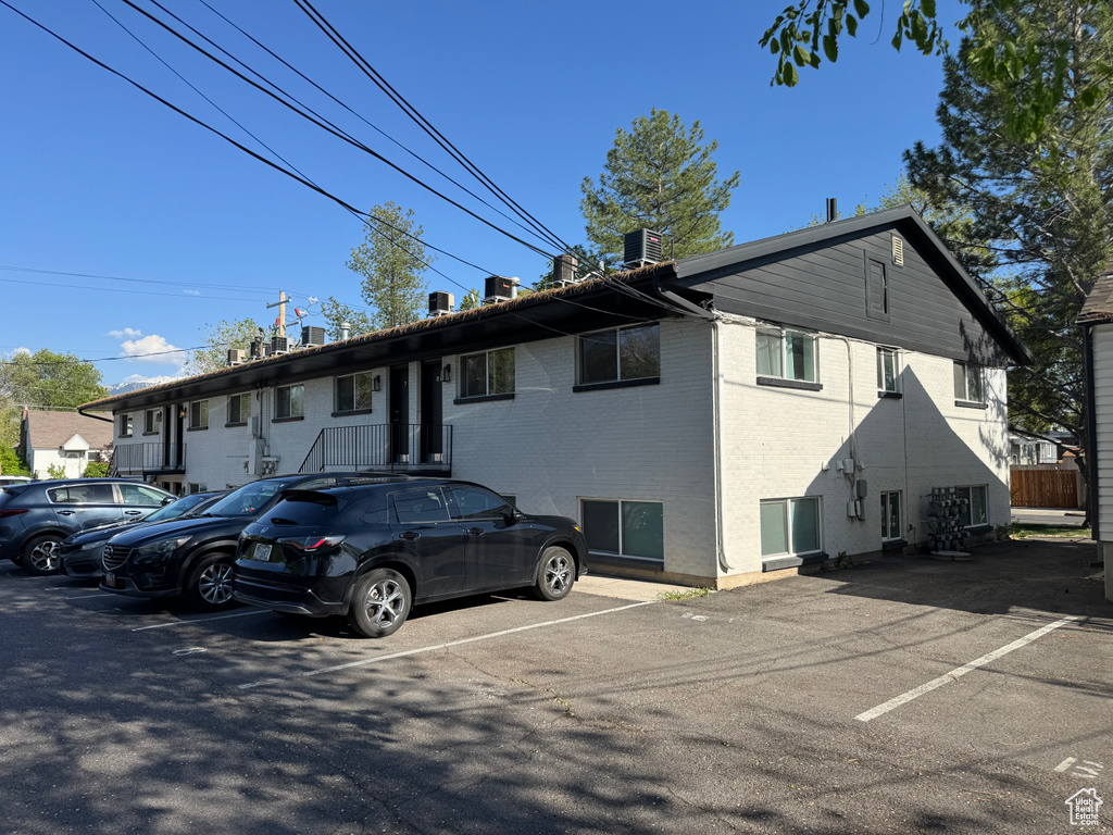Rear view of property featuring uncovered parking, brick siding, and a chimney