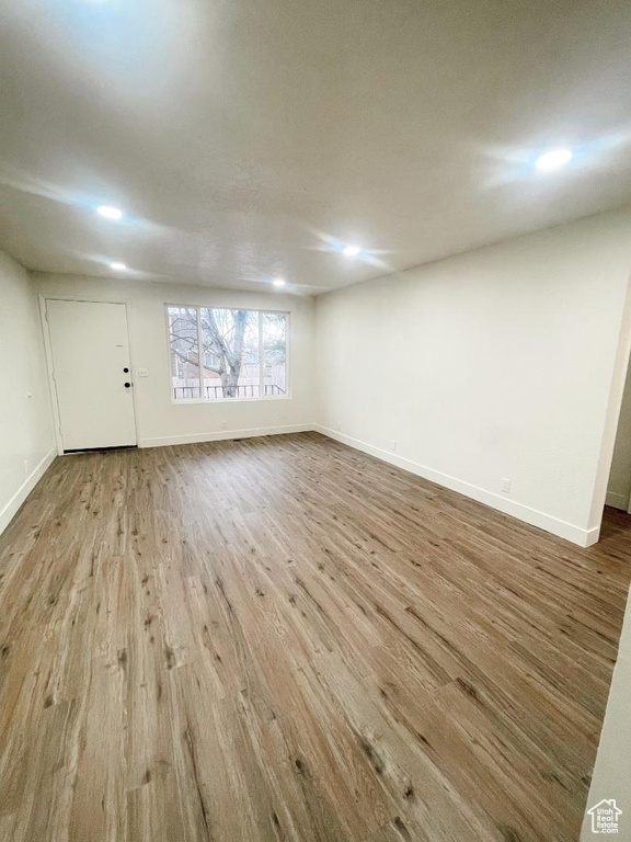 Unfurnished living room featuring wood finished floors, baseboards, and recessed lighting