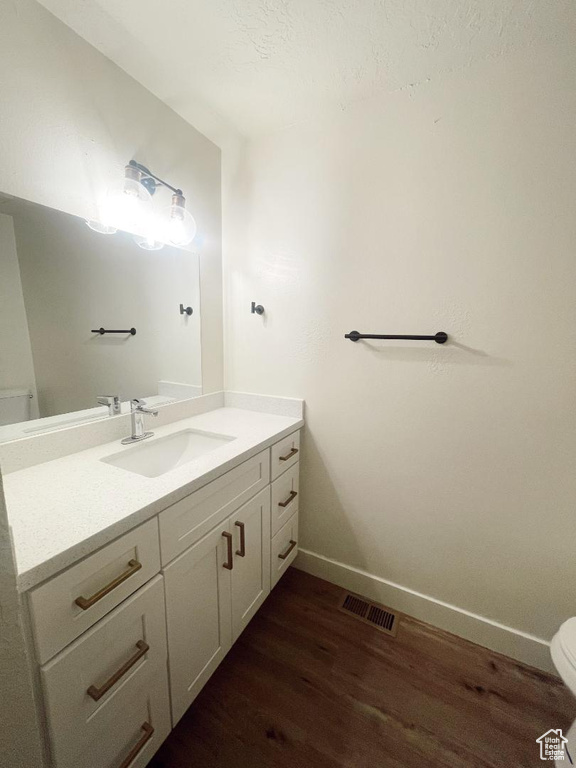 Bathroom with toilet, wood finished floors, vanity, and baseboards
