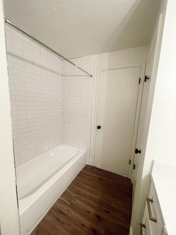 Full bathroom with wood finished floors, a textured ceiling, vanity, and tub / shower combination