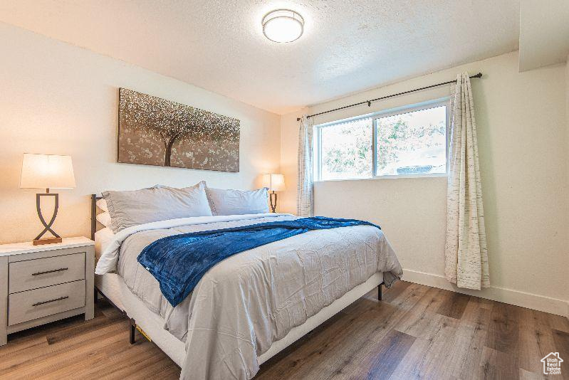 Bedroom featuring light wood finished floors, a textured ceiling, and baseboards
