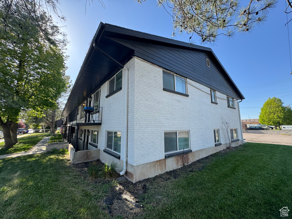 View of side of home with a lawn and brick siding
