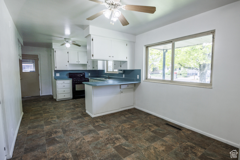Kitchen with black range with gas stovetop, a sink, baseboards, and ceiling fan