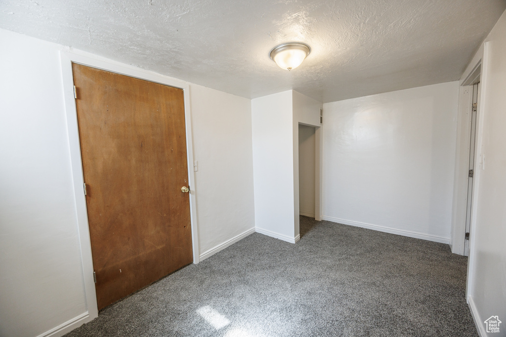 Unfurnished bedroom with carpet flooring, a textured ceiling, and baseboards