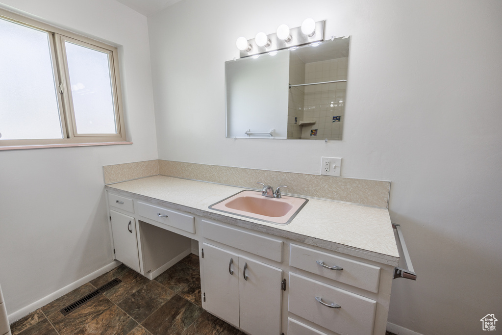 Full bathroom with vanity, a shower, baseboards, and stone finish flooring